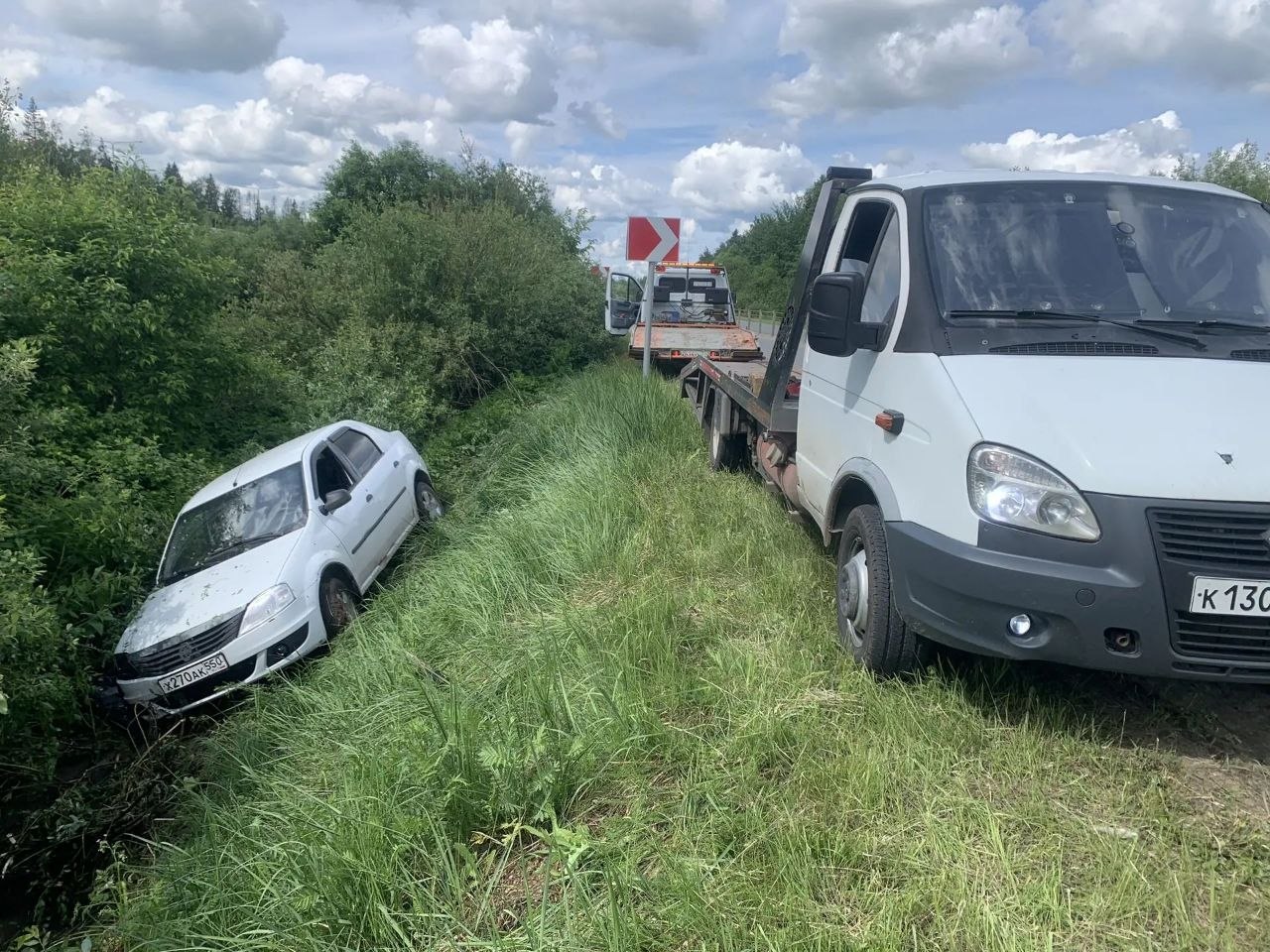 Эвакуатор везёт легковой автомобиль по трассе на рассвете