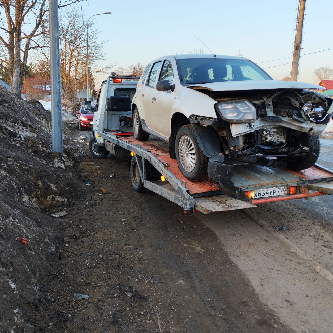 Эвакуатор везёт легковой автомобиль по трассе на рассвете